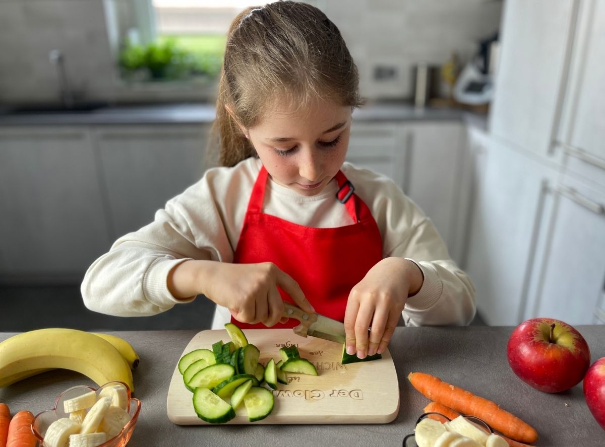 Kind beim Gem&uuml;se schneiden