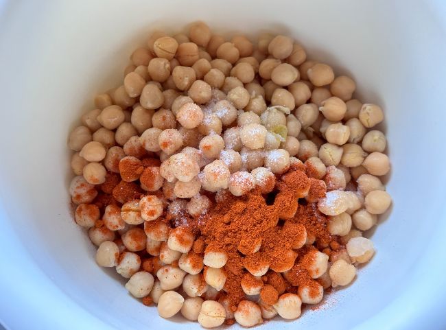 Kichererbsen mit Salz und Paprikapulver in einer wei&szlig;en Sch&uuml;ssel