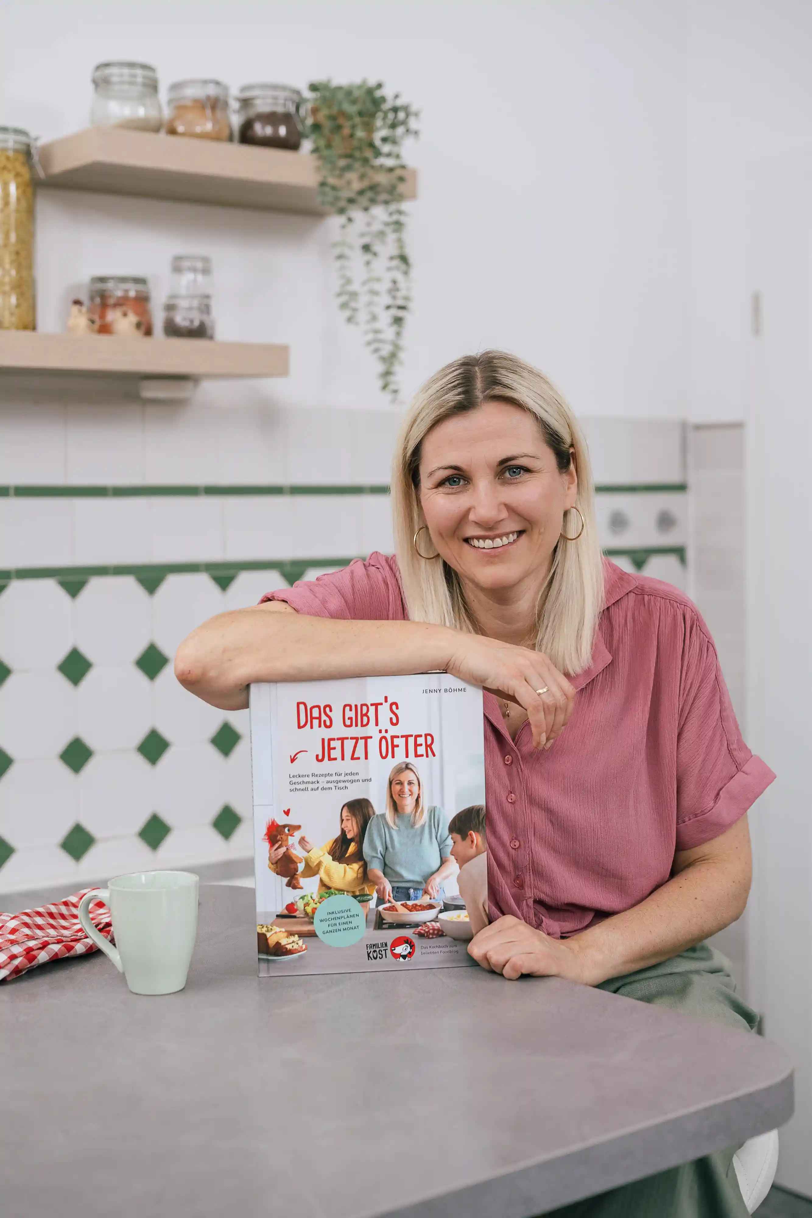 Jenny mit ihrem neuen Kochbuch am K&uuml;chentisch