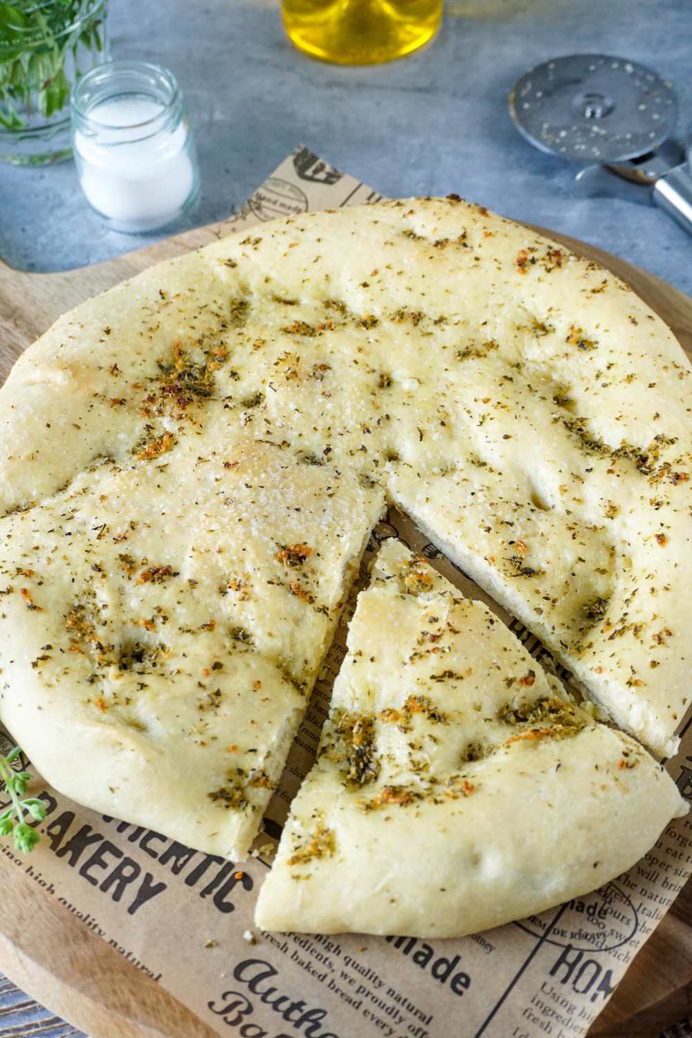 Pizzabrot angeschnitten auf Brett, Pizzaschneider daneben