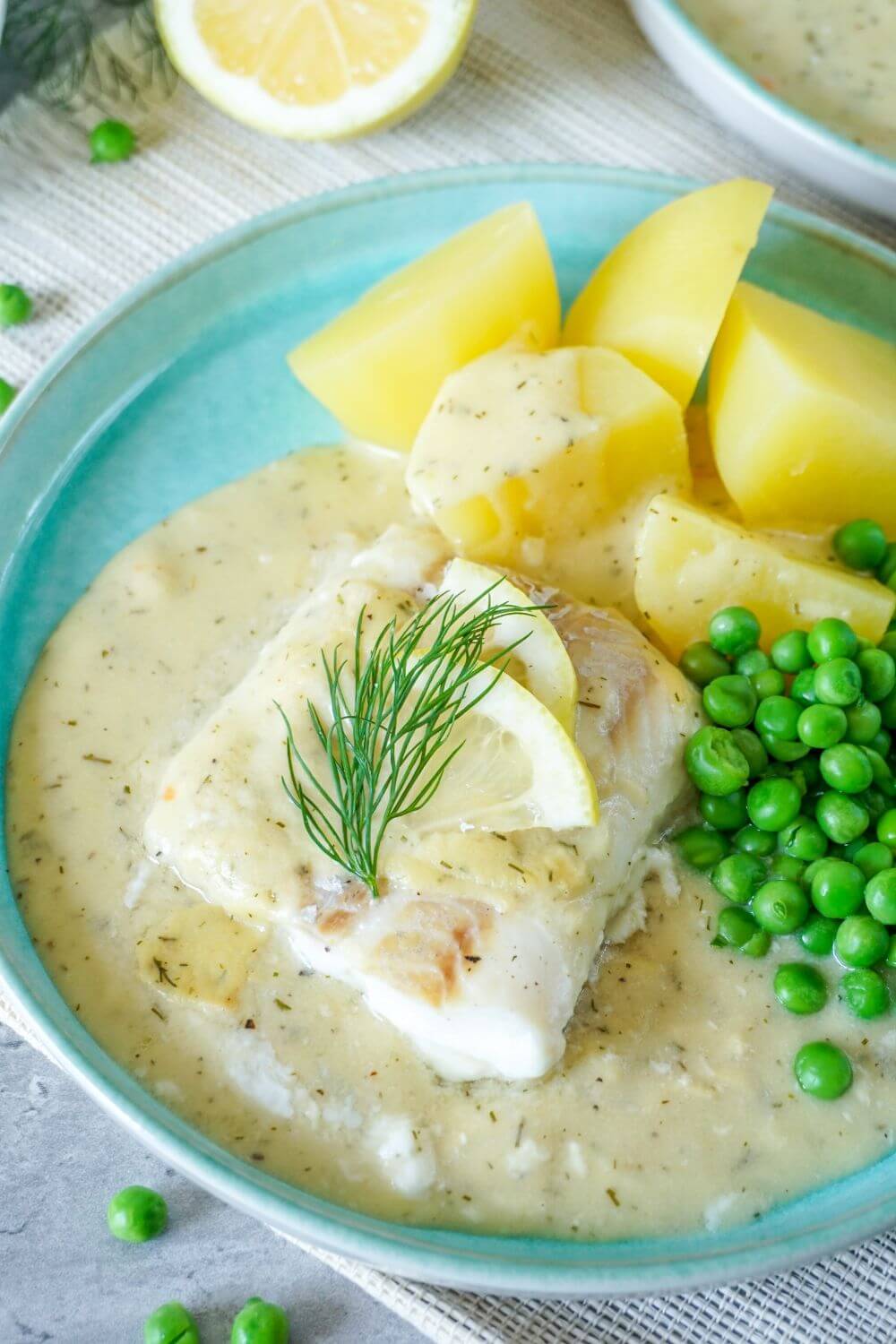 Teller mit Fisch in Senfso&szlig;e, Erbsen, Kartoffeln und Dill