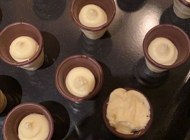 Kuchen im Waffelbecher - Teig mit einem Teelöffel verteilen Kuchen im Waffelbecher - Teig mit einem Teelöffel verteilen